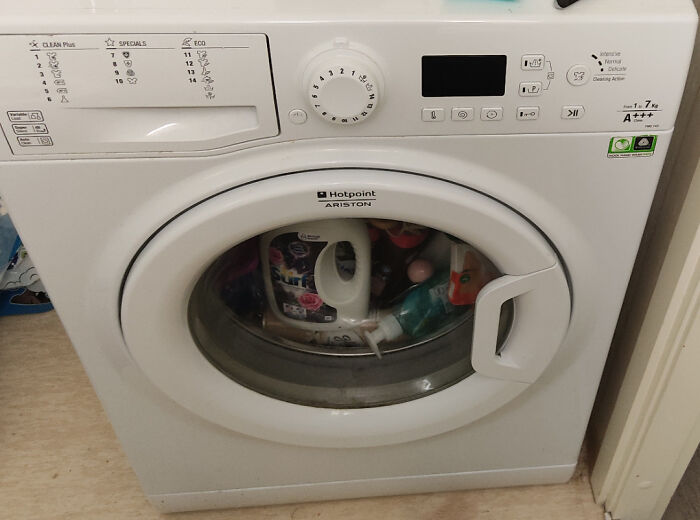 Washing machine stuffed with laundry detergent and items, a sign of horrible roommates.