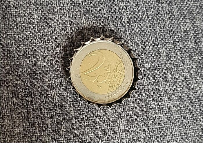 Coin perfectly fitting inside a bottle cap on textured fabric, illustrating a satisfying perfect fit.