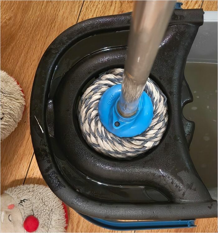 "Perfectly fitted mop in bucket with satisfied plush slippers on wooden floor."