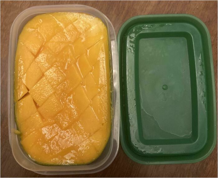 Perfect fit: sliced mango neatly packed in a container beside its matching green lid.