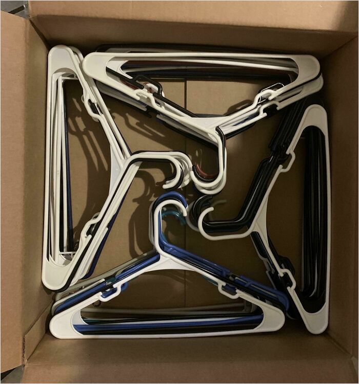 A box of hangers arranged in a satisfying perfect fit, showcasing precise organization.