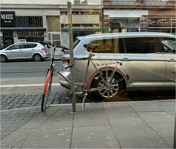 Bicycle parked with front wheel perfectly aligned with a car’s wheel, showcasing a satisfying perfect fit.