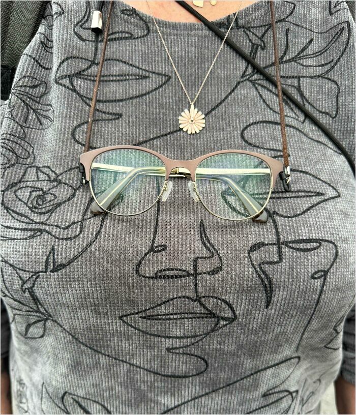 Eyeglasses hanging on a necklace with sketch art shirt, creating a satisfying perfect fit illusion.