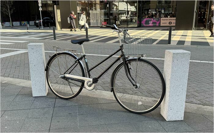 Bike parked between two posts, showcasing a satisfying perfect fit on a city sidewalk.