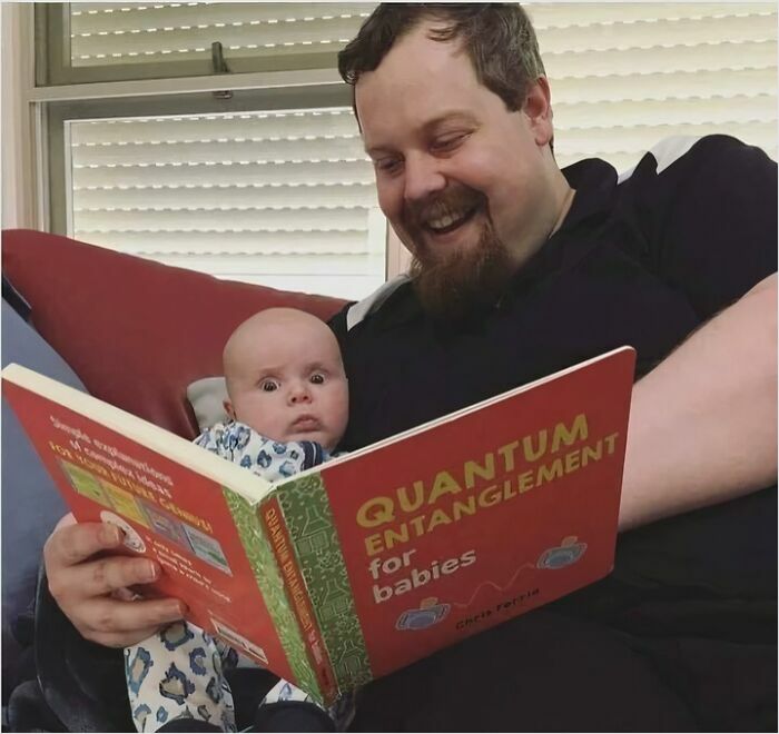 Man reading a "Quantum Entanglement for Babies" book to a surprised baby, highlighting science memes humor.