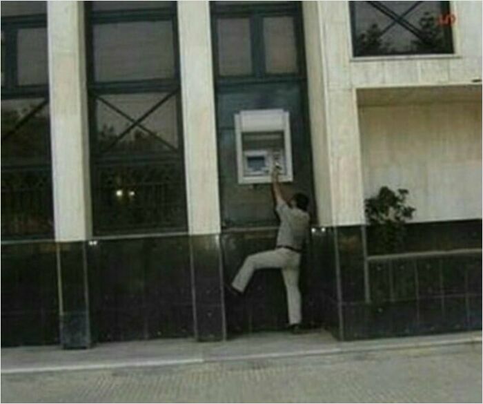 Construction worker humorously reaching for a poorly placed ATM.