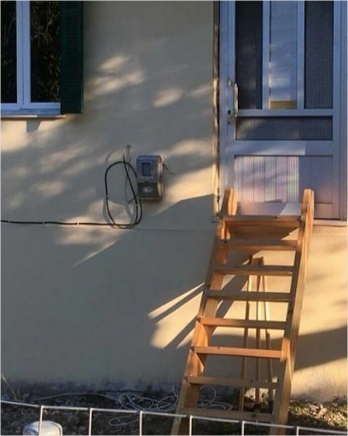 A wooden staircase leading to a door placed too high, highlighting construction mishap humor.