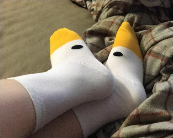 Cozy, stylish yellow-tipped socks with a black dot, perfect for lounging on a plaid blanket.