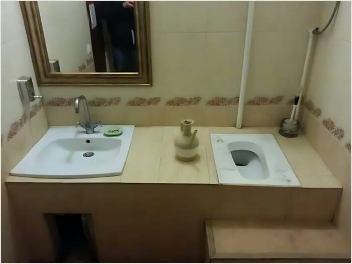 Bathroom construction fail with awkward sink placement next to toilet.