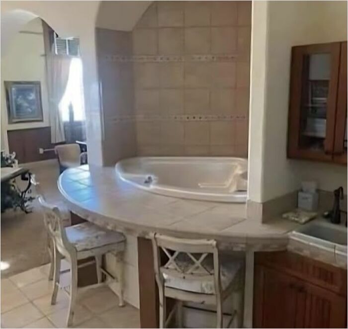 Bathtub awkwardly placed behind a kitchen counter, showcasing a hilarious construction fail.