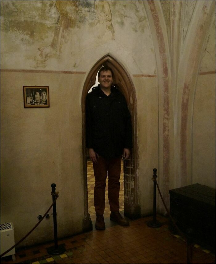 Man standing perfectly in a narrow arched doorway, achieving a satisfying perfect fit.