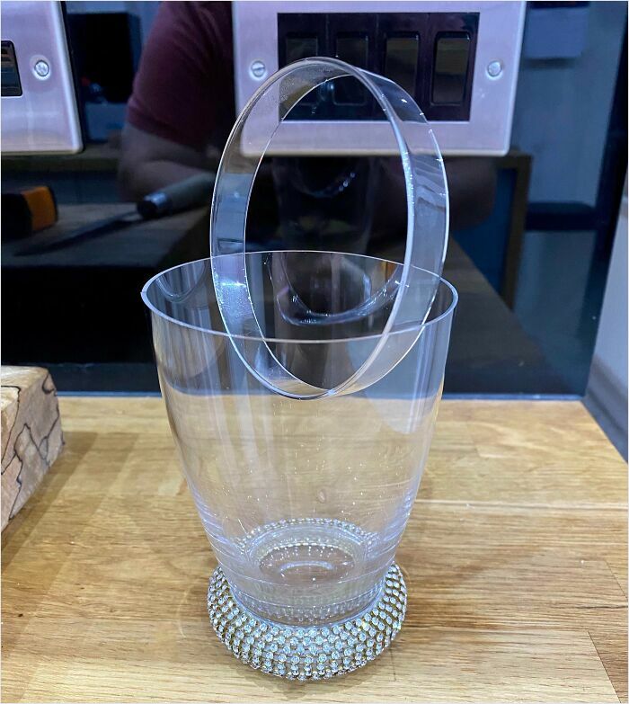 Clear plastic ring perfectly fitting into a matching glass on a wooden table.