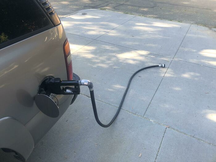 Car driving away with a gas pump nozzle still attached, illustrating a common mistake seen in "Idiots In Cars".