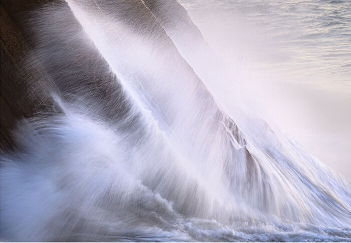 Dynamic wave captured crashing against rocks, showcasing fascinating ocean movement.