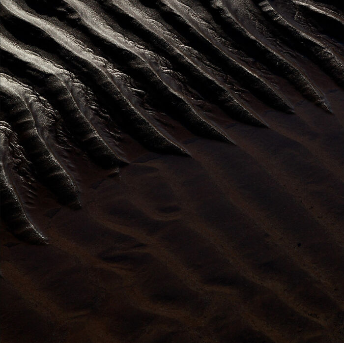 Abstract photo of dark, textured waves on sand captured by a photographer.