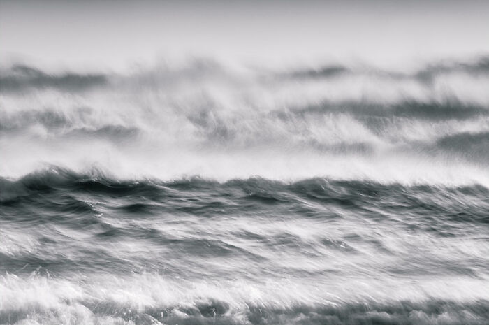 Black and white photo of ocean waves captured by a photographer, showcasing their fascinating movement and texture.