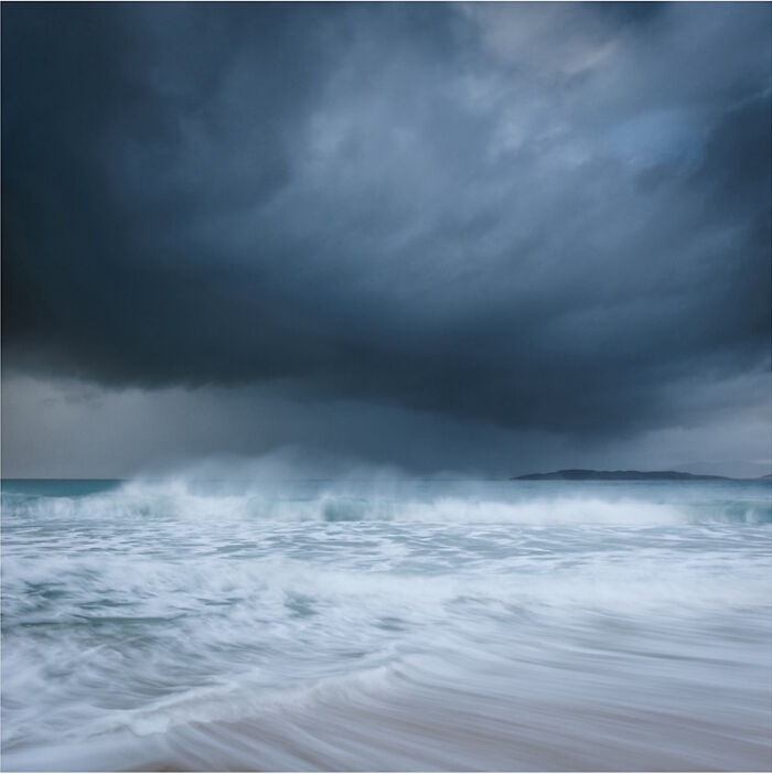 Stormy ocean waves rolling under dark clouds, captured by a photographer.