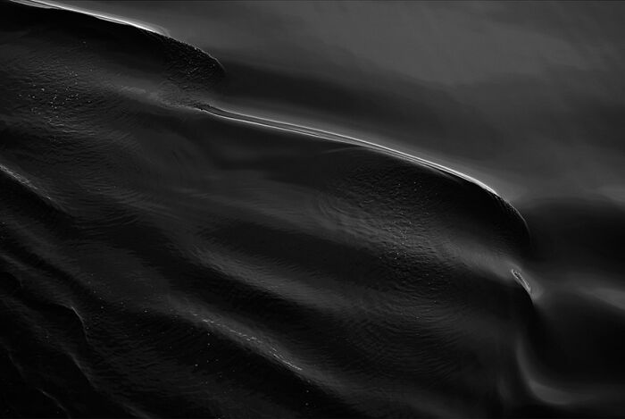 Black and white photograph of ocean waves with captivating textures and light reflections.