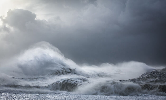 Dramatic ocean waves captured by photographer under stormy skies.