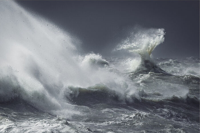 Photographer captures powerful ocean waves crashing dramatically in a stormy sea scene.