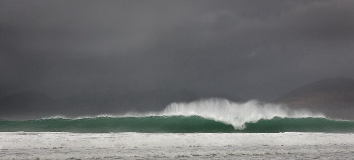 Stormy ocean wave captured dramatically against dark skies, showcasing fascinating photography.