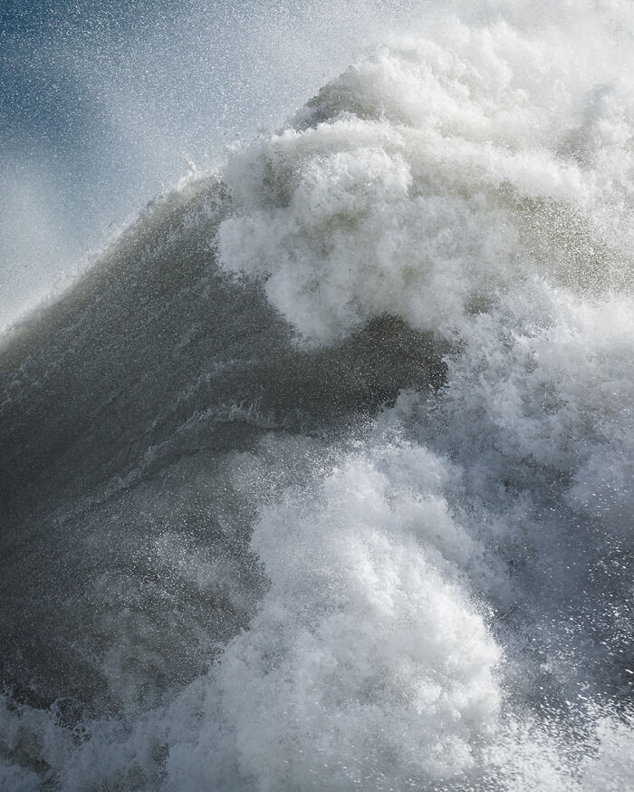 Dynamic ocean wave captured by photographer, showing layers of frothy water in motion.