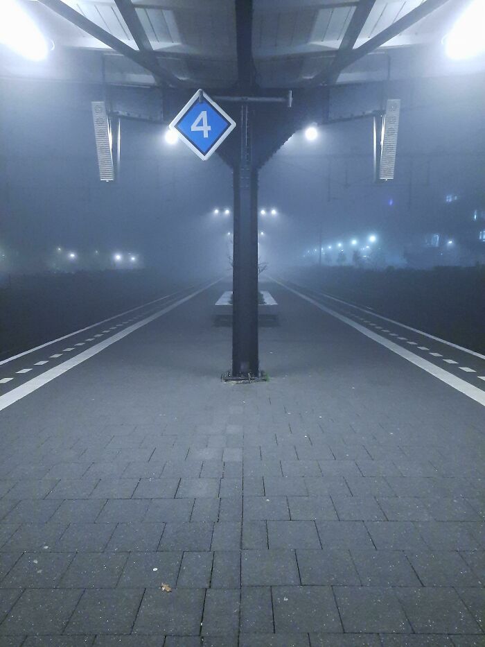 Foggy train station platform resembling a videogame scene with glowing lights and a "4" sign overhead.