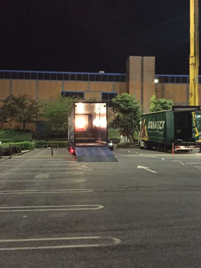 Truck with open cargo bay illuminated at night, resembling a scene from a videogame.