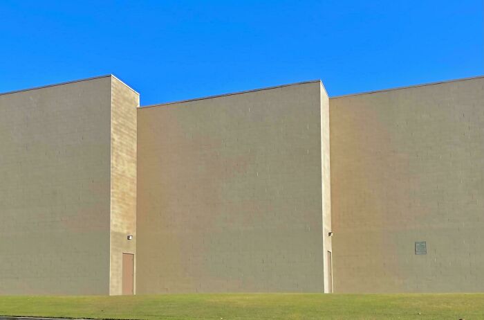 Building exterior with minimalistic design resembling videogame graphics under a clear blue sky.