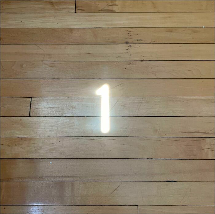 Light reflecting a number 1 on wooden floor, resembling video game graphics.