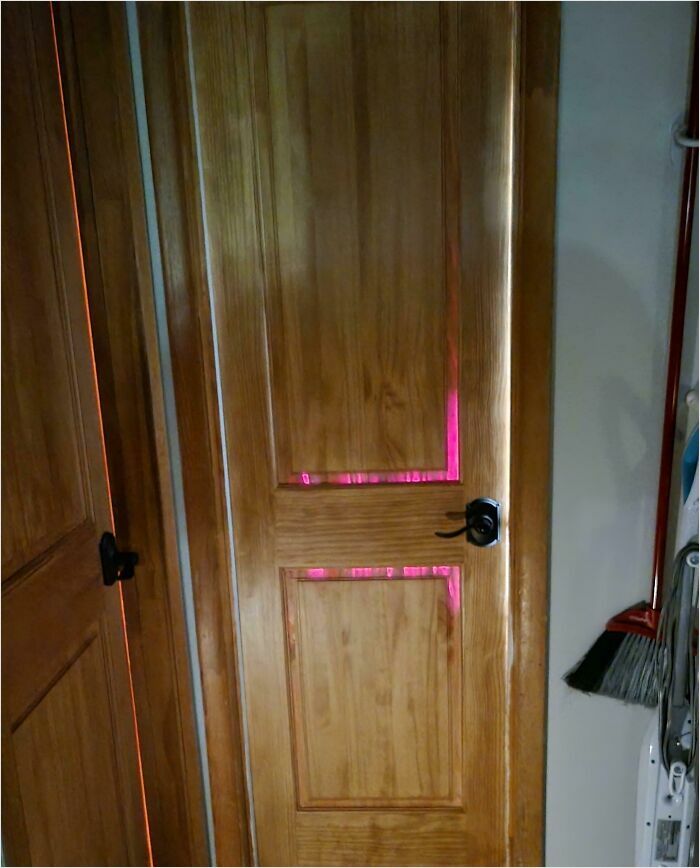 Wooden door with pink light seeping through edges, resembling a scene from a videogame.