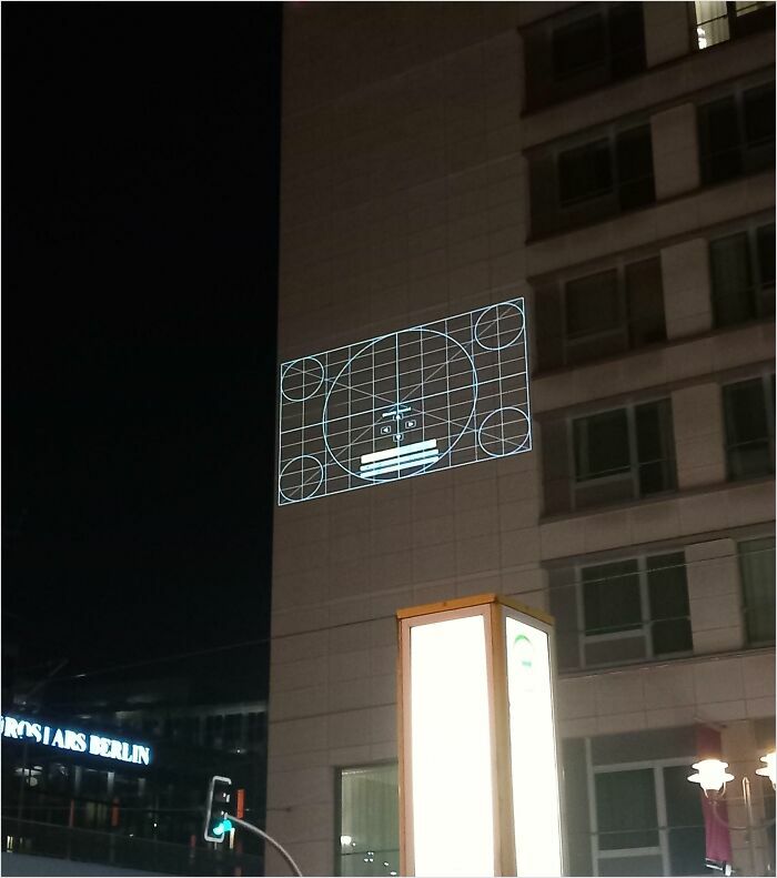 Building facade at night with a projected grid, resembling a video game level.