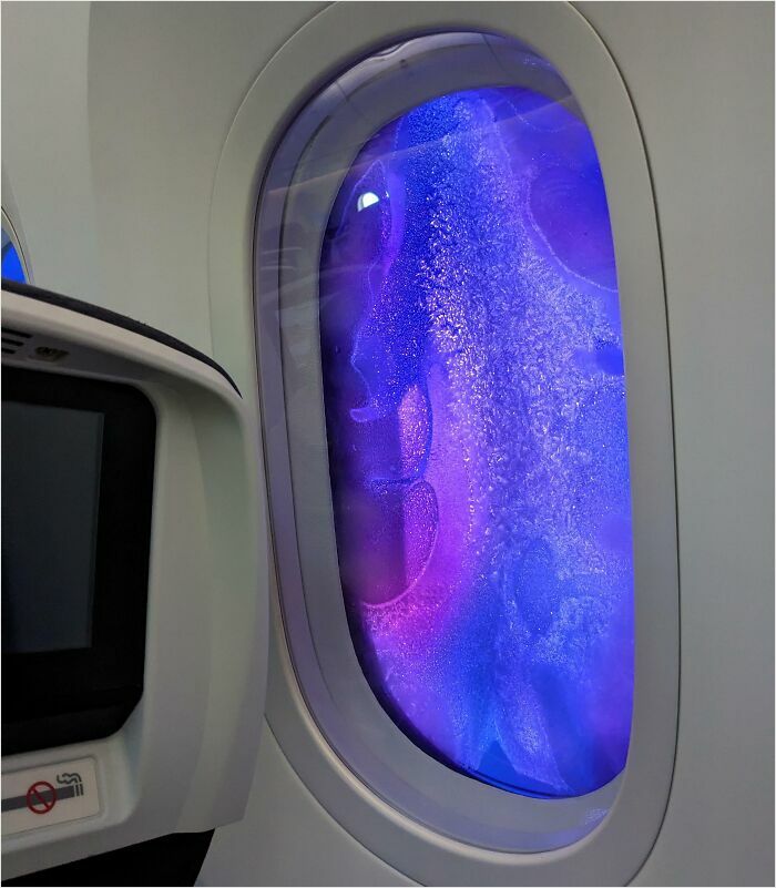 Airplane window with vibrant purple and blue hues, resembling a scene from a videogame.