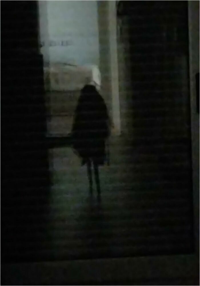 A dark, shadowy figure in a dim hallway resembles a scene from a videogame.