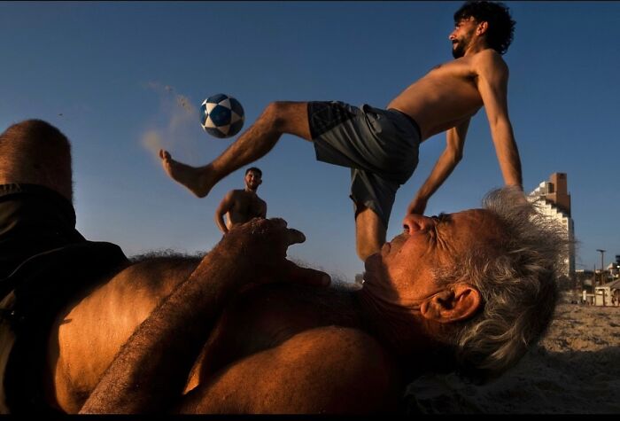 Men playing beach soccer in Tel Aviv, Israel, captured by Ilan Ben Yehuda during sunset.