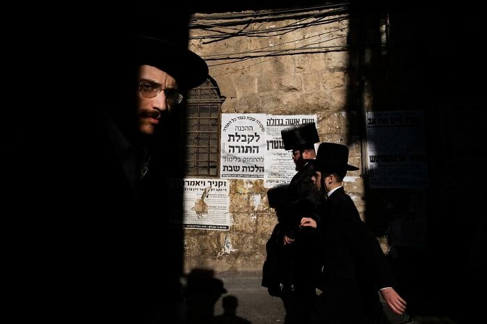 Street scene in Israel with men in traditional attire, captured by Ilan Ben Yehuda.