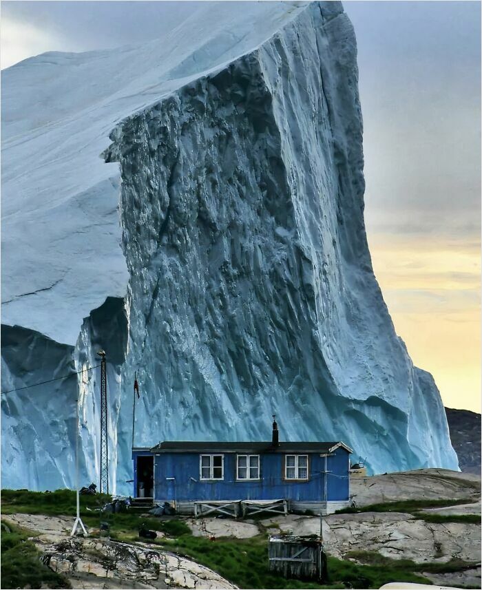 Iceberg Passing By A House In Greenland