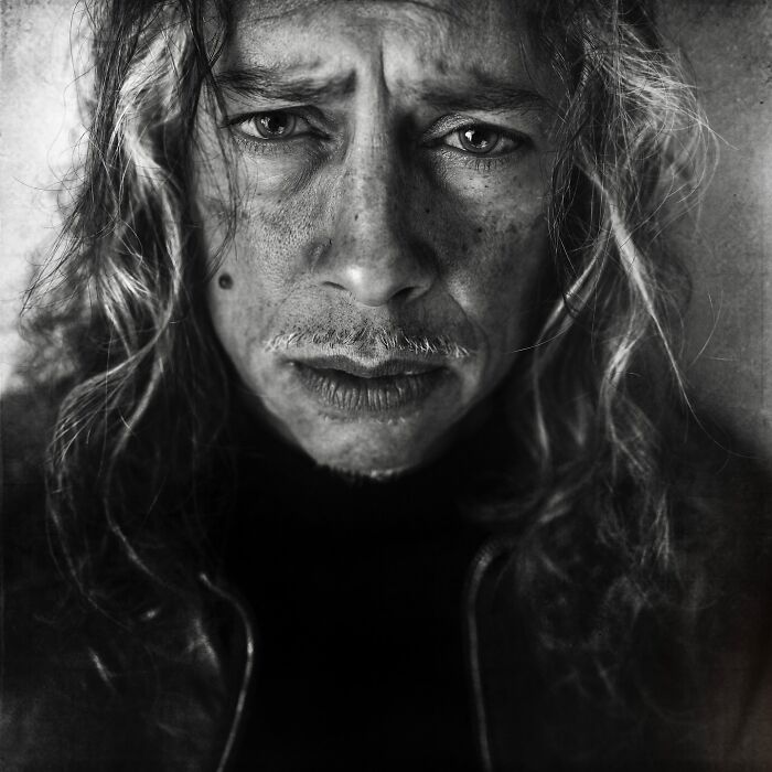 Soulful black and white portrait by Lee Jeffries featuring a man with long hair and intense expression.