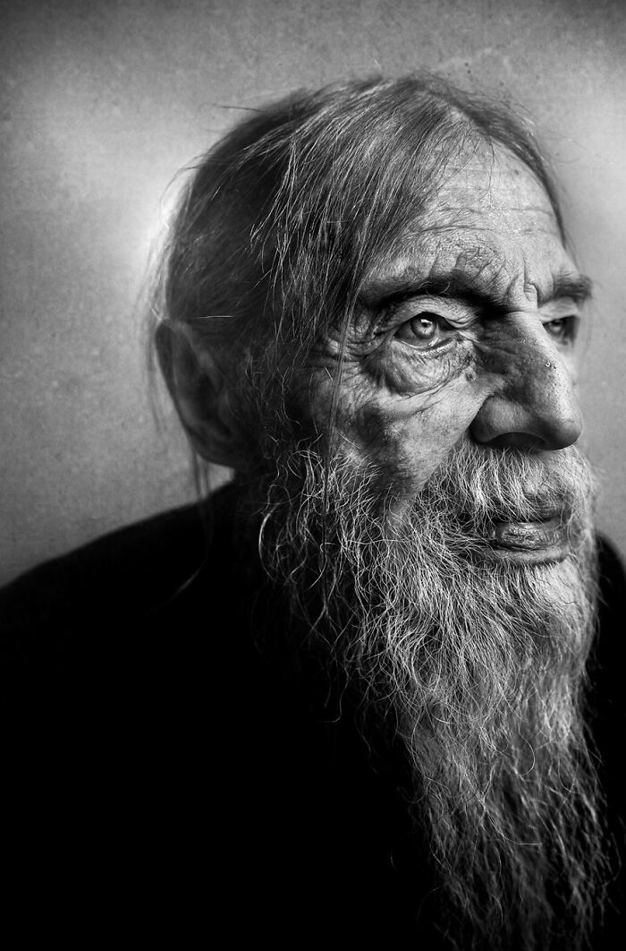 Soulful portrait of an elderly man with a long beard, highlighting expressive eyes, photographed by Lee Jeffries.