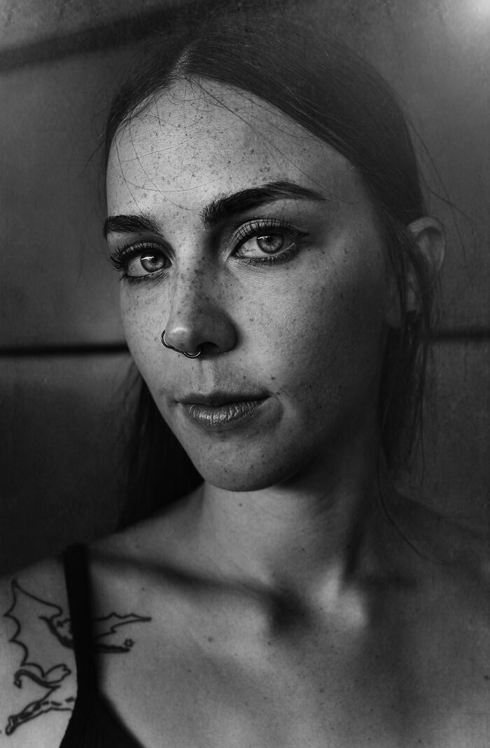 Soulful portrait by Lee Jeffries of a woman with a nose ring and tattoo, showcasing expressive eyes and freckles.