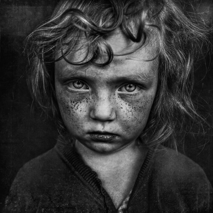 Soulful portrait of a young girl with intense eyes, taken by Lee Jeffries, capturing raw emotion and depth.