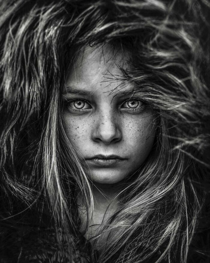 Close-up black and white portrait by Lee Jeffries of a person with intense eyes and flowing hair.