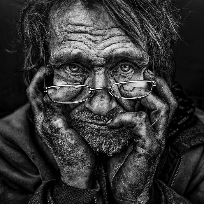 Soulful portrait by Lee Jeffries capturing an older man with glasses, deep-set eyes, and a weathered face.