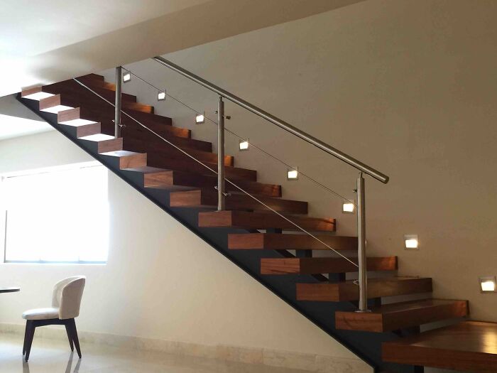 Staircase with wooden steps and metal railing in a minimalist space, resembling a bad render.