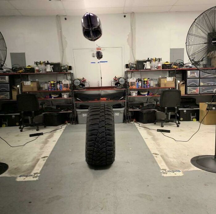 A floating tire in a mechanic's shop, resembling a 3D render amidst shelves and chairs.