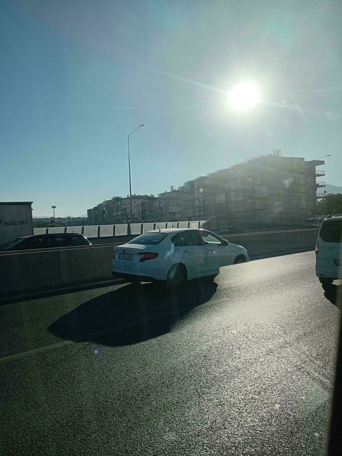 Cars on a highway under a bright sun, appearing like a digital render.