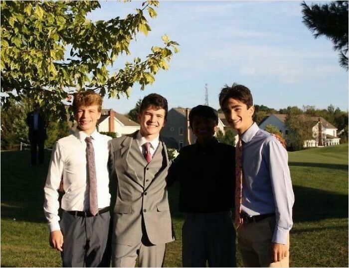 Four young men posing outside, one appears in shadow, creating a visual effect like bad renders in real-life photos.