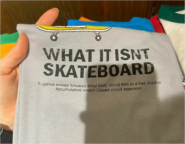 T-shirt with humorous translation in Japan, featuring text "WHAT IT ISN'T SKATEBOARD" and assorted phrases.