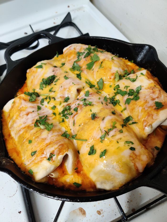 Cheesy enchiladas in a cast-iron skillet, garnished with fresh cilantro.