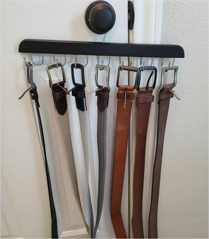 Belt organizer on a door, featuring multiple belts neatly arranged for efficient space use.